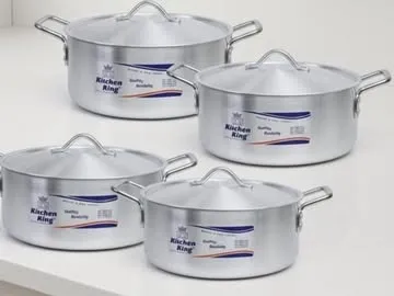 Four polished aluminium casseroles with domed lids on a white counter